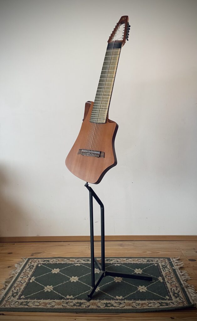Mounted on a stand this is Dragonfly Tapping Instruments semi acoustic, nylon string model of their 12-stringed instrument made for   tapping/touchstyle technique. 